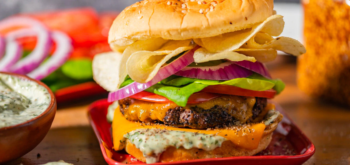 Close up on burger with spread, cheese, lettuce, tomato, and potato chips