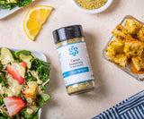 Medium jar of Caesar Seasoning with strawberry caesar salad, croutons, and lemon wedge