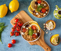 Overhead shot of two finished bowls of Mediterranean Dill Risotto garnished with feta cheese, tomatoes, and lemon